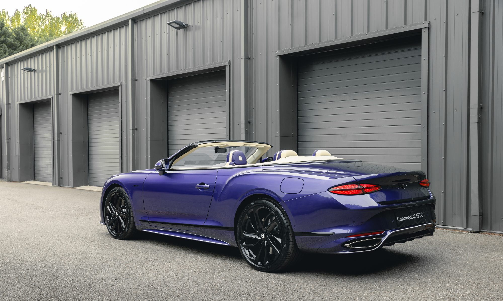 Bentley Continental GTC Speed in Violette finish with top down parked in front of a garage left rear three quarter view.