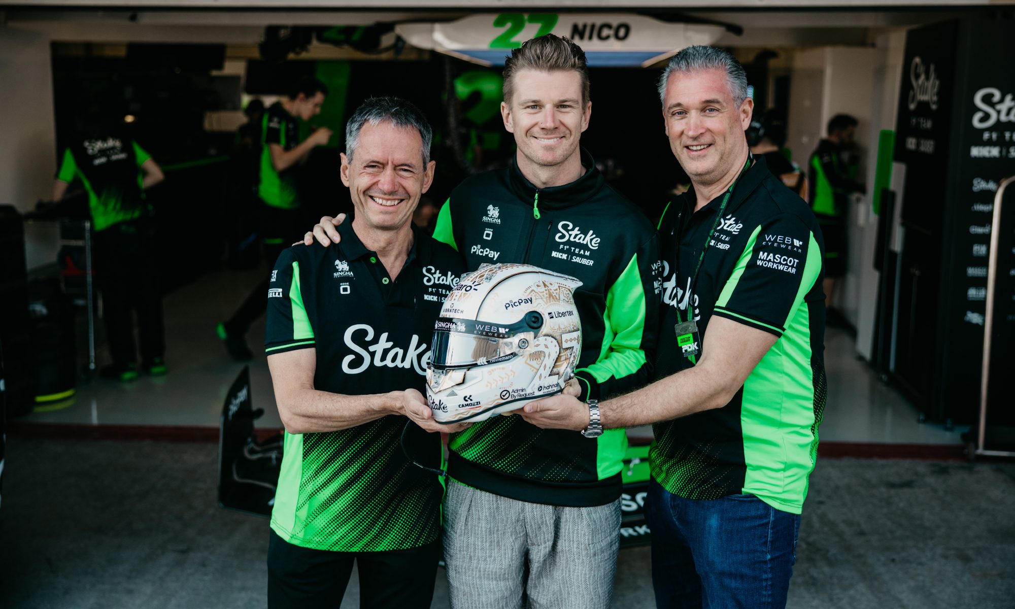 Nico Gormsen Founder of Hahnair Foundation, Nico Hulkenberg, and Daniel Rudas Chief Operating Officer for Hahnair holding helmet in the pit lane.