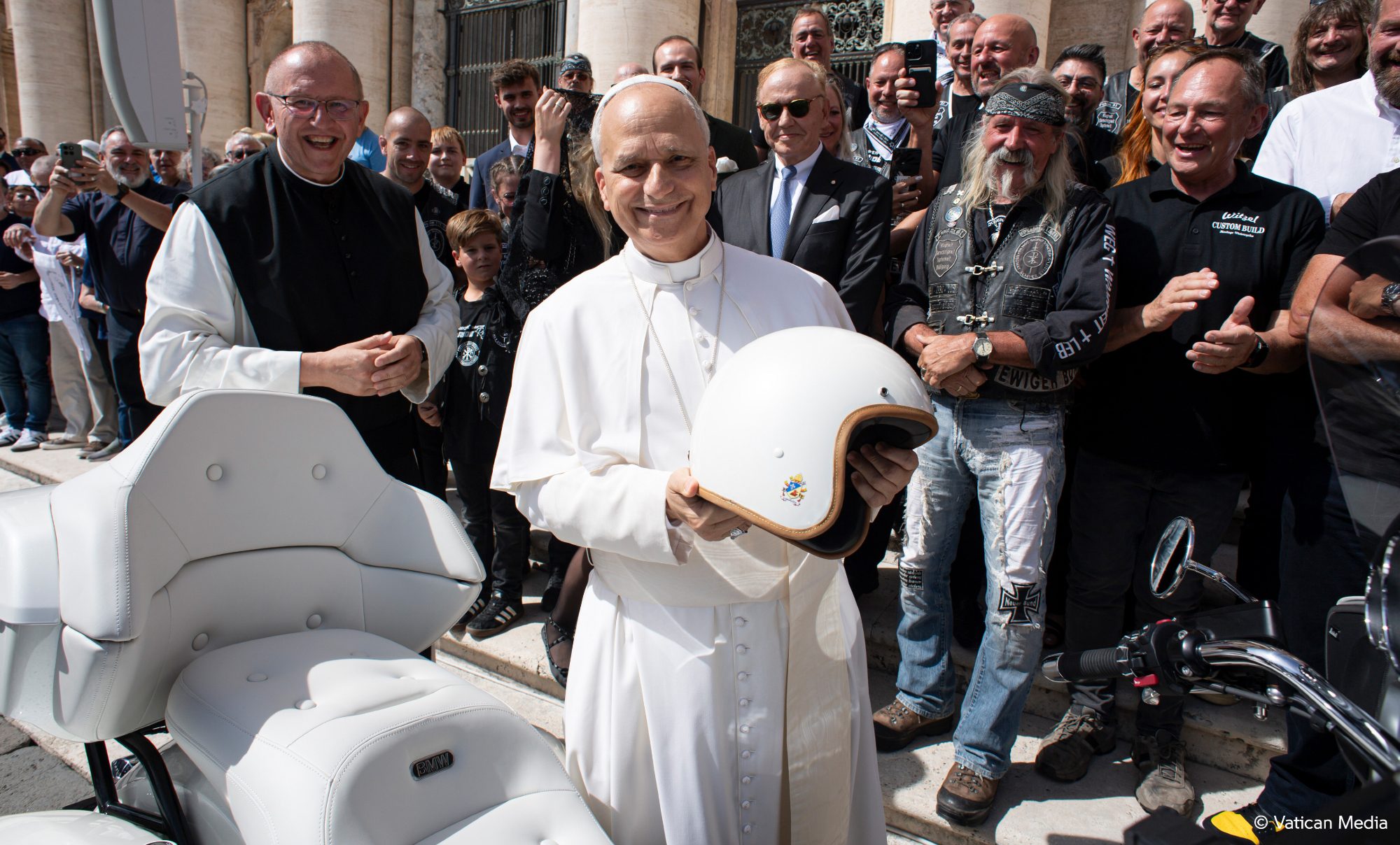 Pope Leo XIV holding a white helmet while standing next to the 2025 BMW R 18 he signed.