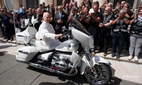 Pope Leo XIV sitting on the 2025 BMW R 18 he signed in front of a sidewalk full of applauding people.