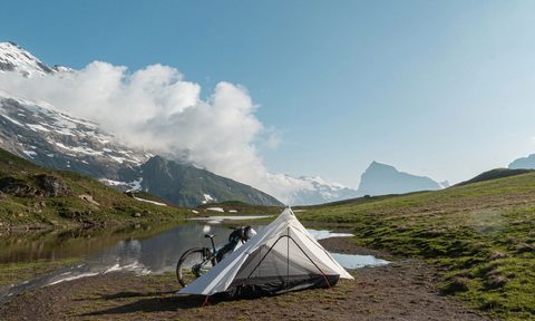 Aper Apex1 solo bikepacking tent pitched near an alpine lake.