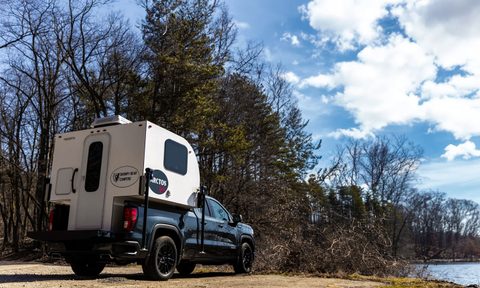 Grumpy Bear Campers' Arctos Sport truck camper parked near a lake.