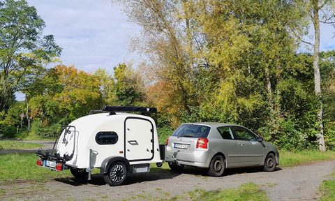 Kleox Festival teardrop travel trailer being towed by a compact European car.
