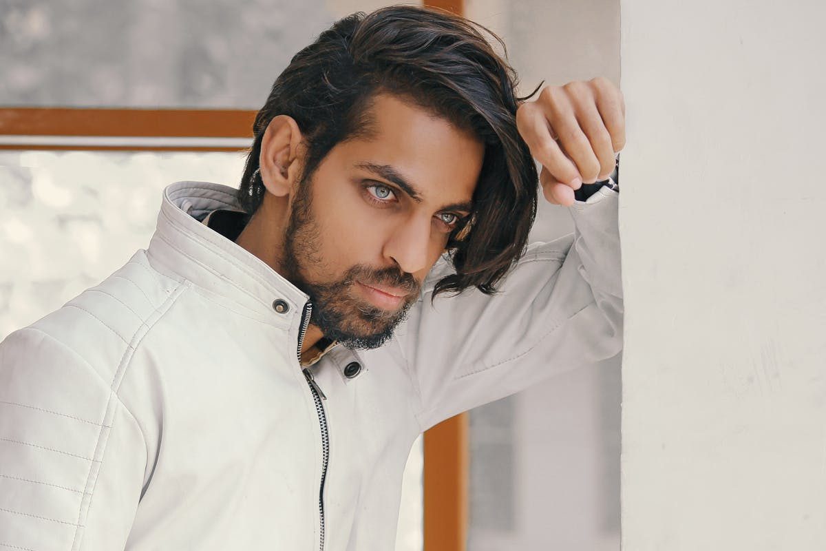 man with long hair leaning onwall
