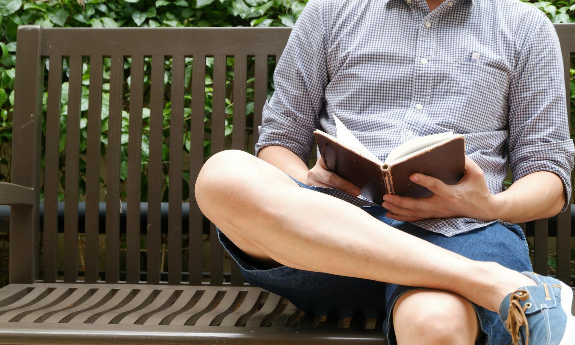 man reading a book on a bench