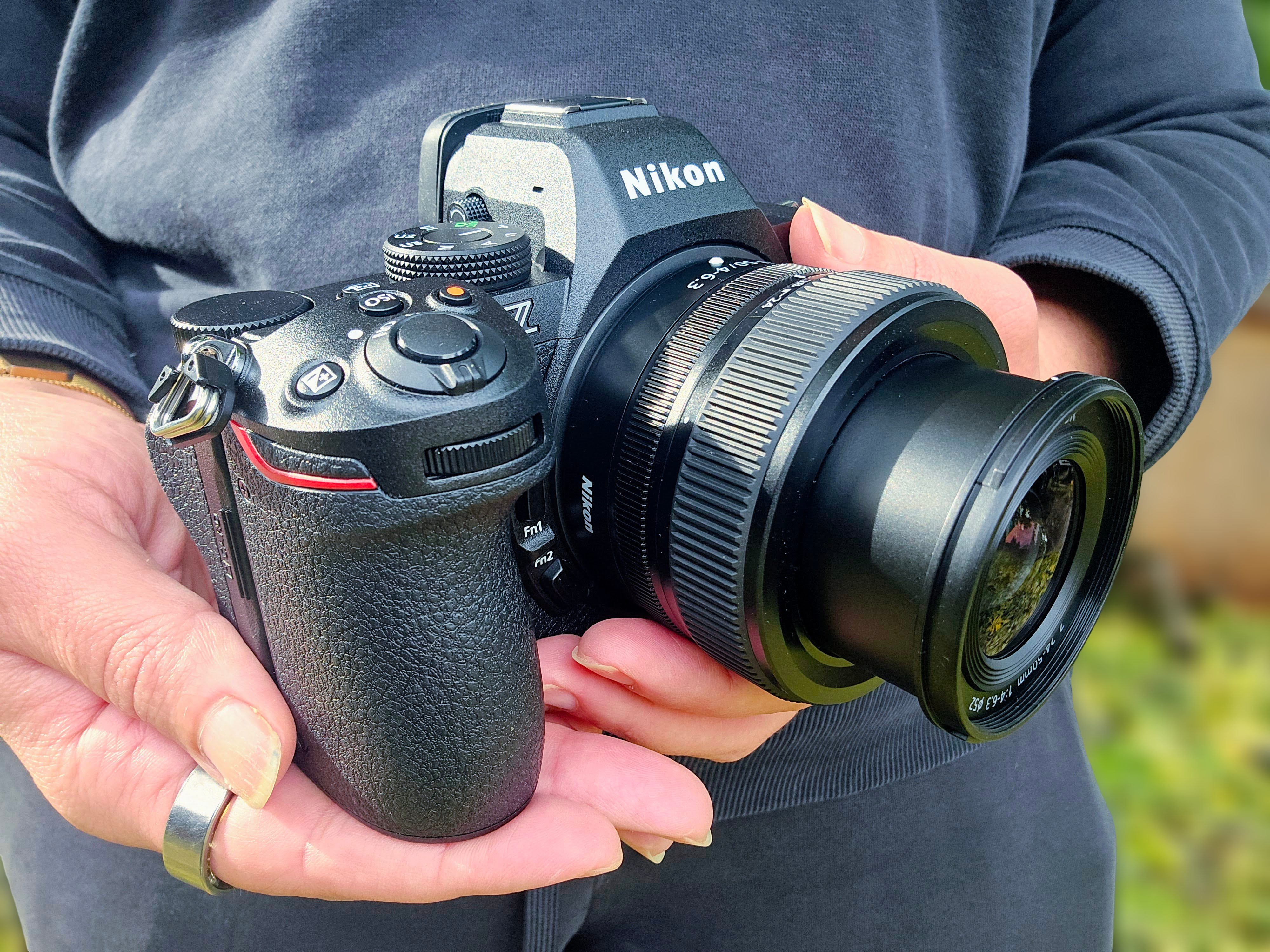A person holding the Nikon S5 II camera in their hands outside