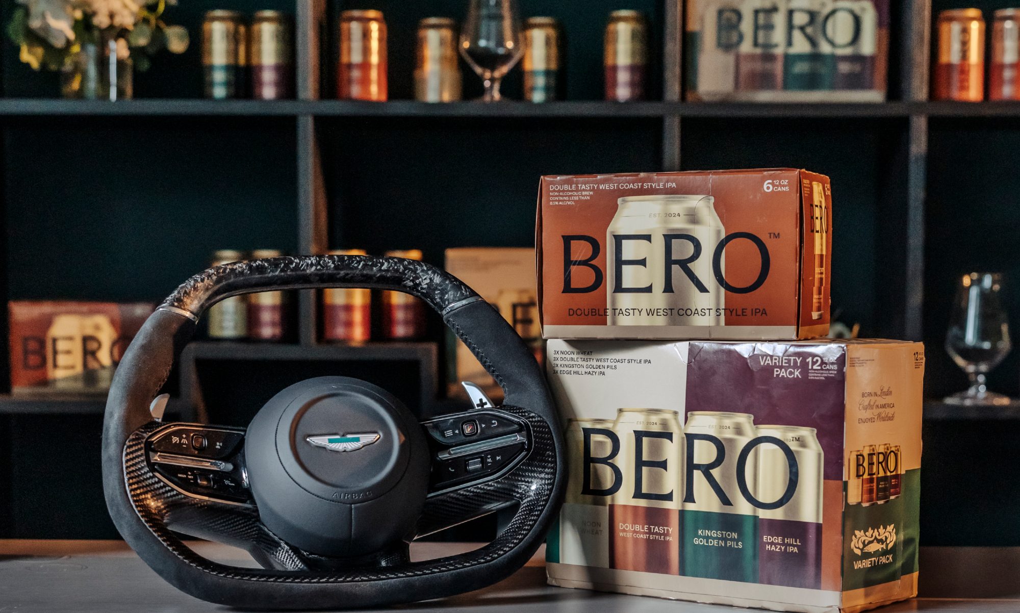Aston Martin steering wheel next to BERO beer cases and cans on shelves.