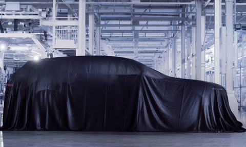 Bentley's first electric vehicle covered by a black tarp.