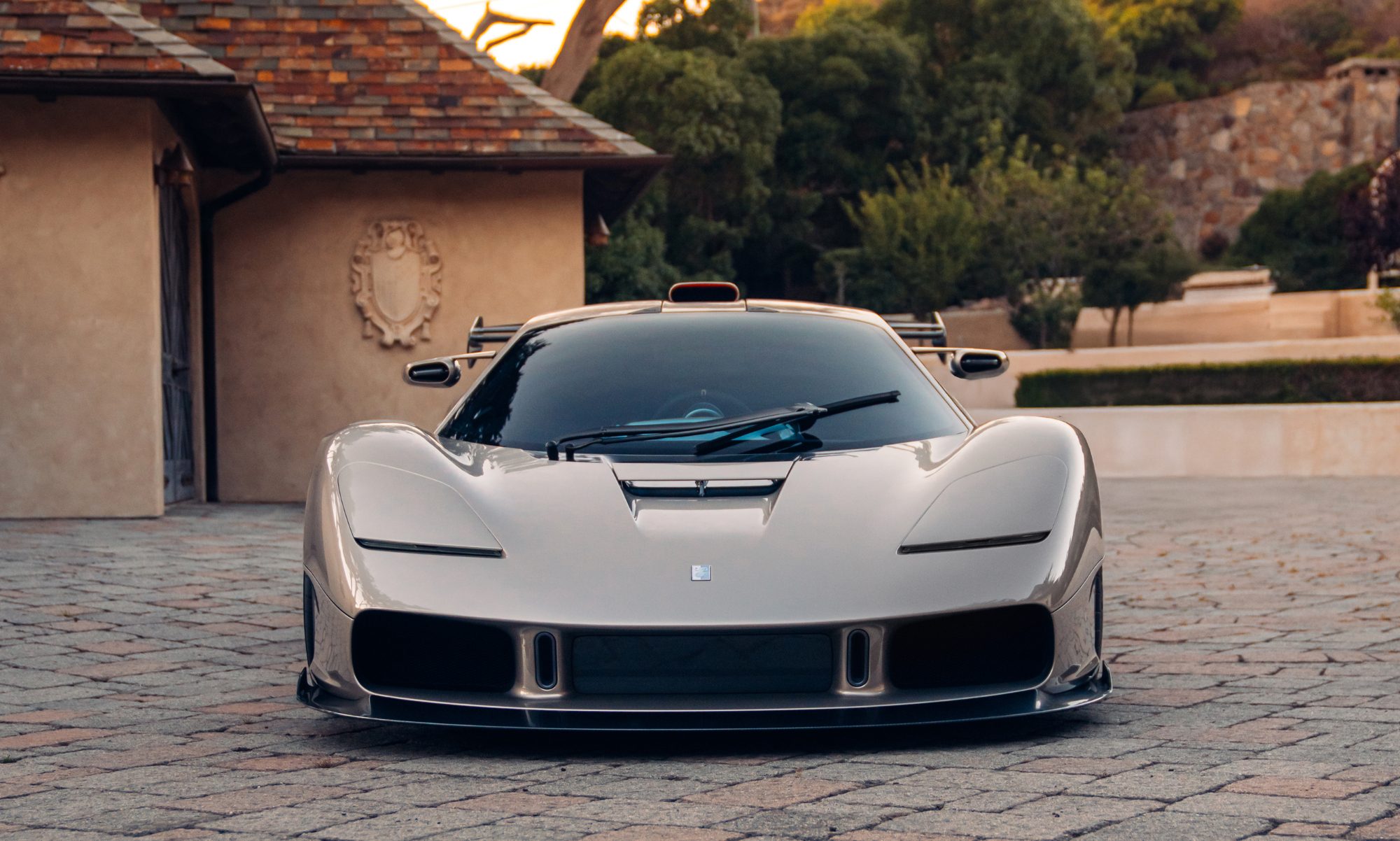 Gordon Murray S1 LM supercar parked on a stone drive courtyard direct fontal view.