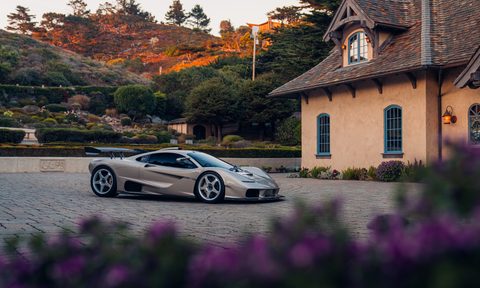 Gordon Murray S1 LM supercar parked on a stone drive courtyard outside a brick building surrounded by lavish landscaping right front three quarter view.