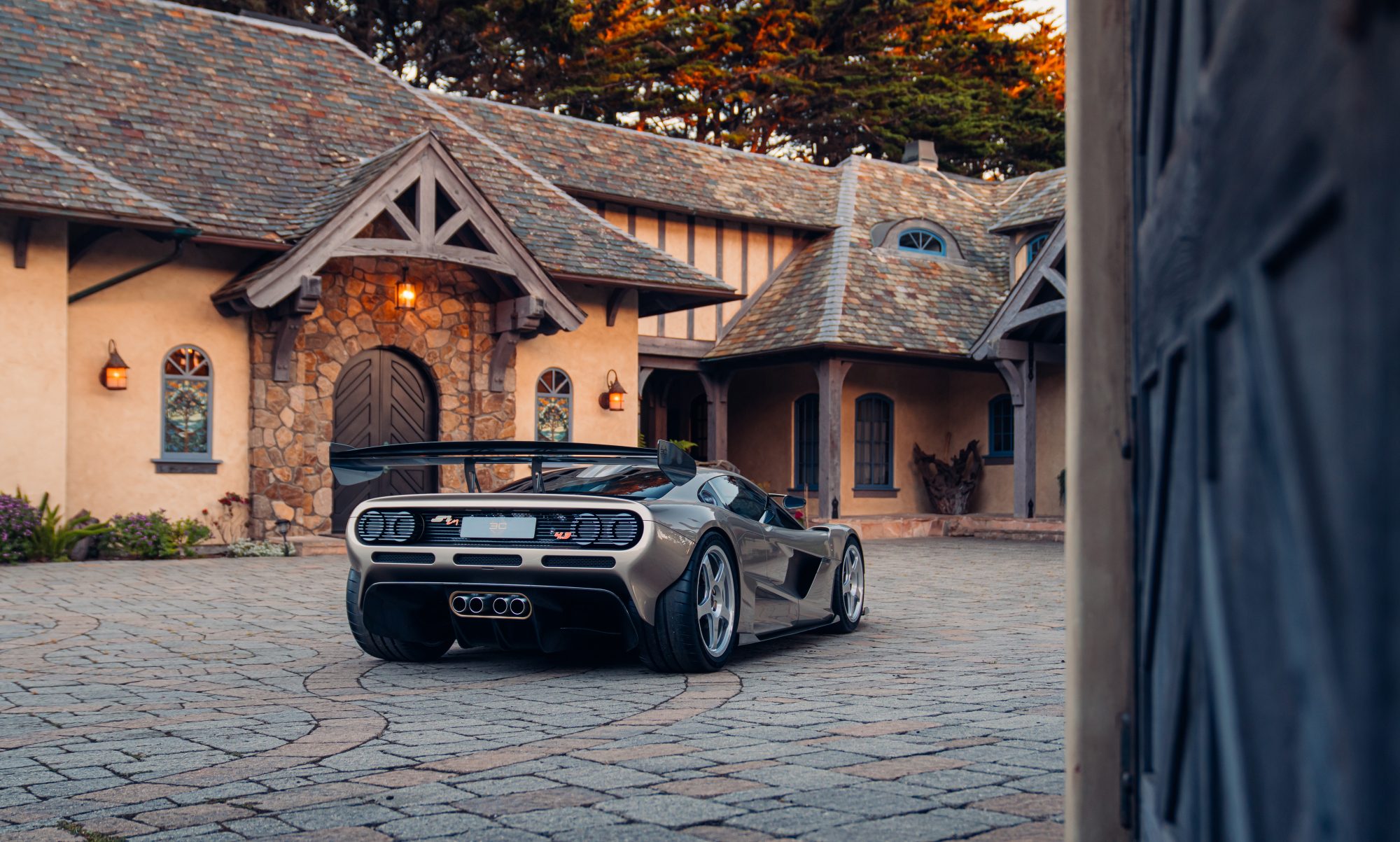 Gordon Murray S1 LM supercar parked on a stone drive courtyard right rear three quarter view.