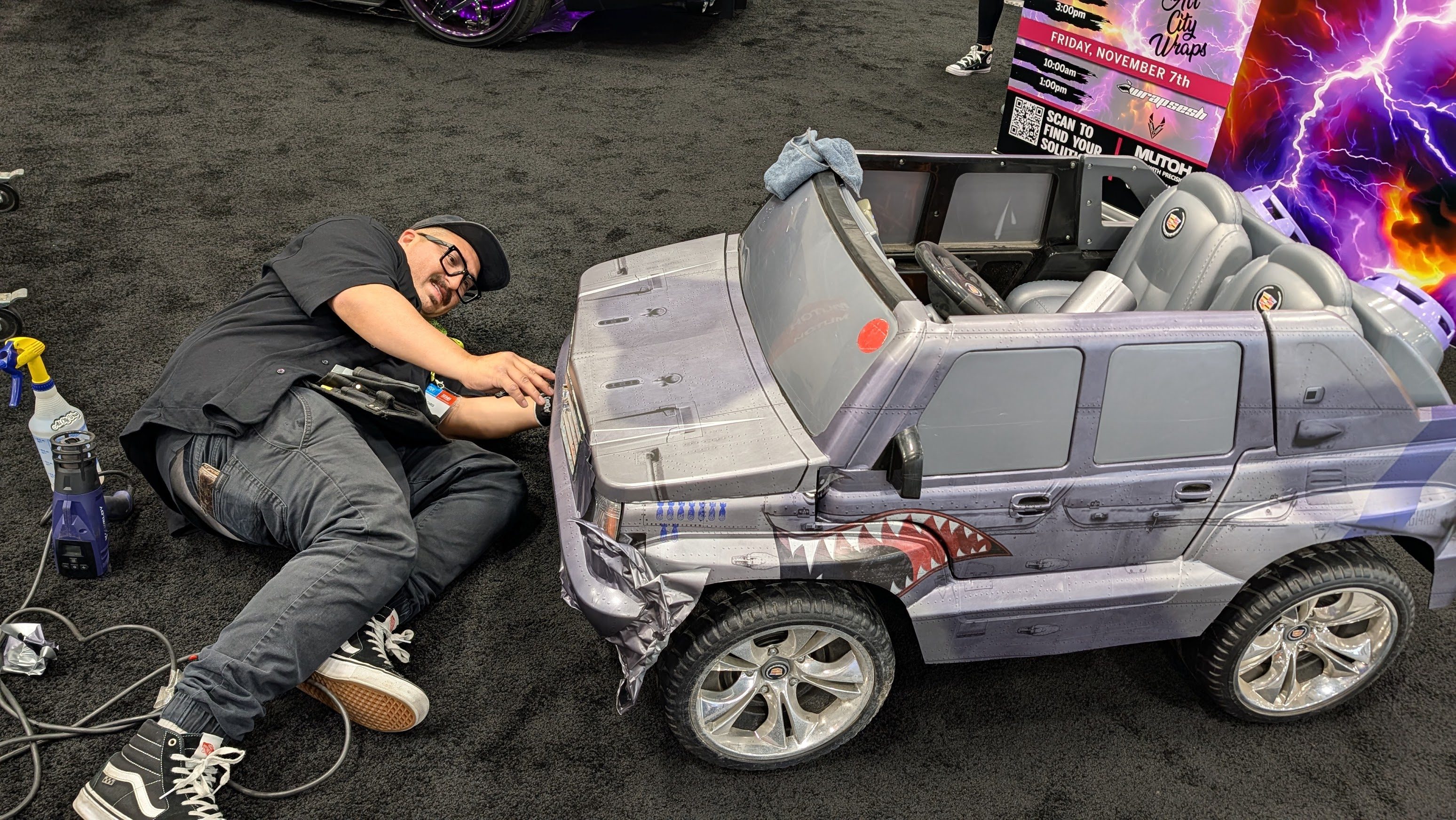 A man applying a wrap to a child's electric toy car