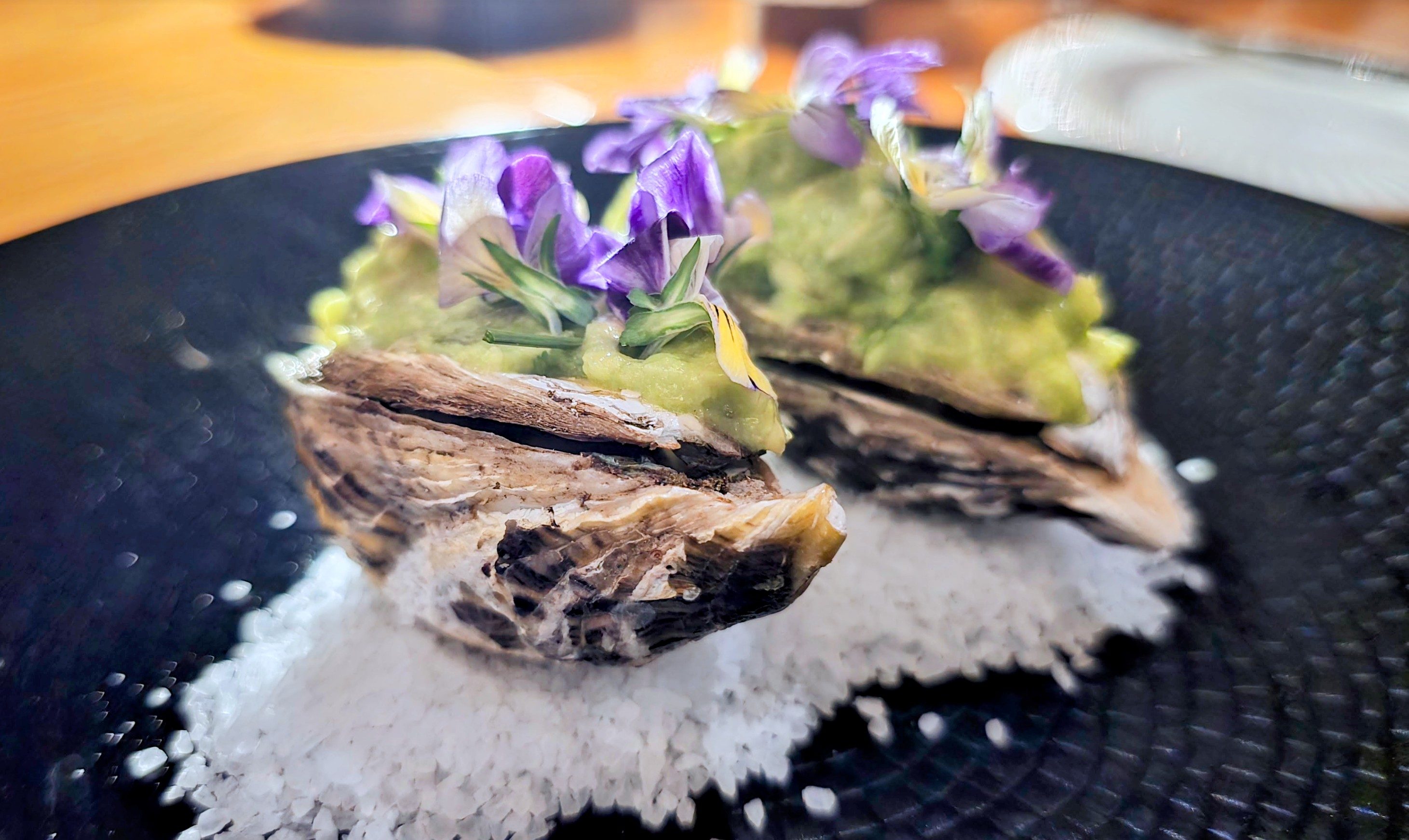 two oysters on a bed of salt topped with flowers