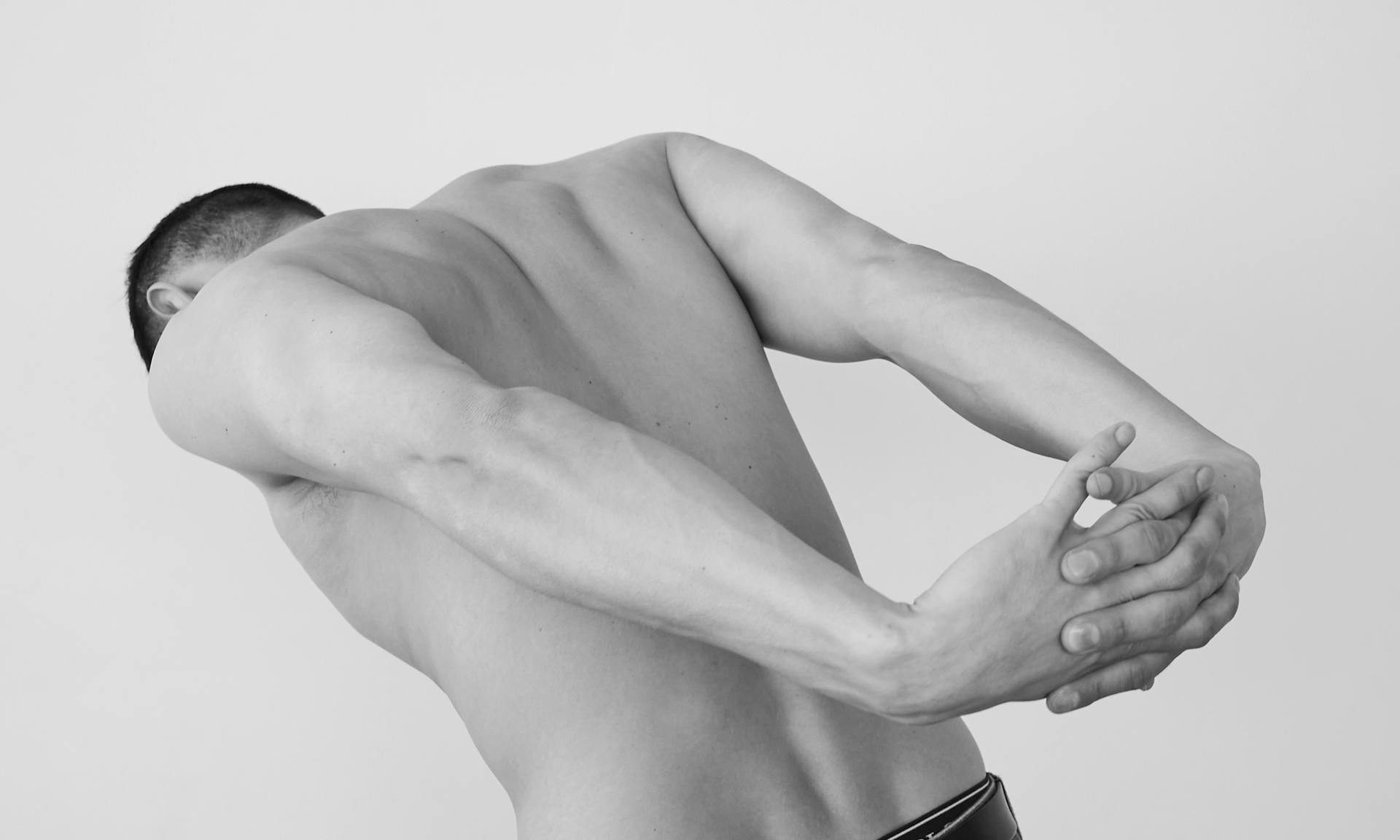 man stretching back neck shoulders