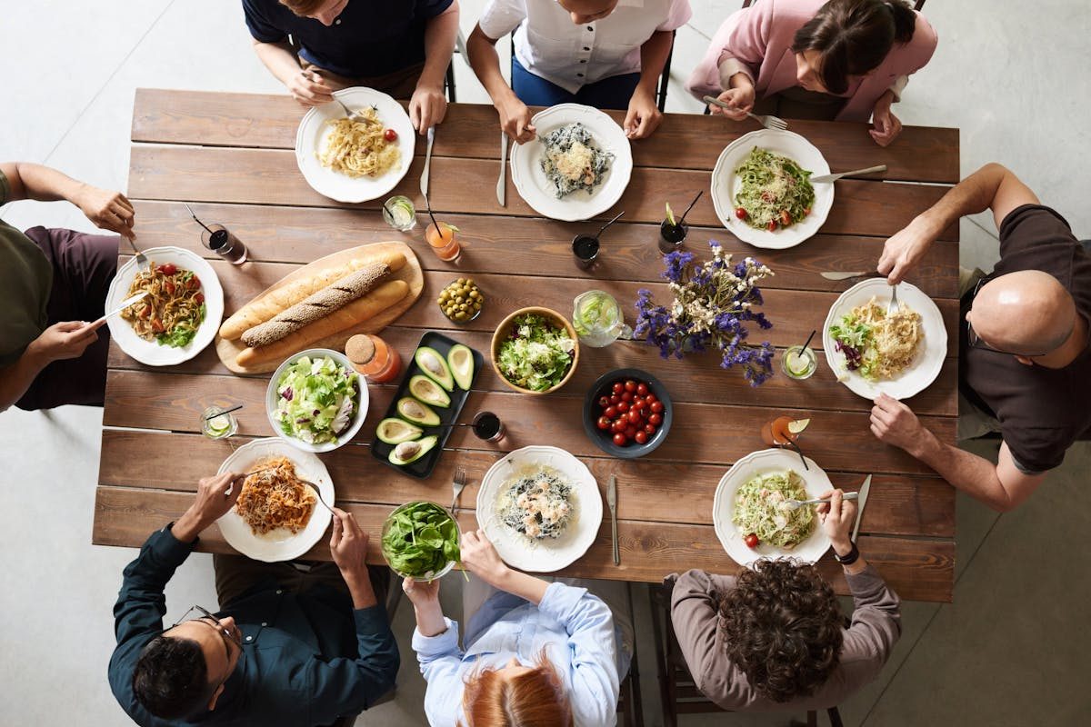 people sitting round a wooden table eating