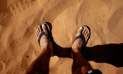 man foot sandals in the sand beach
