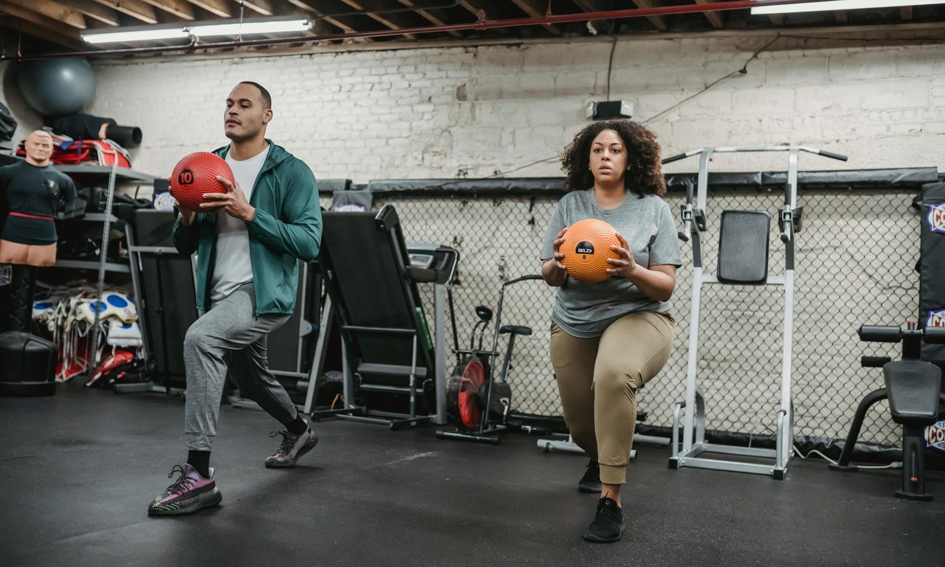 man and woman doing lunge with medicine ball in gym
