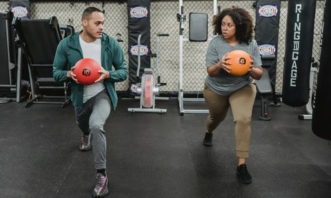 man and woman lunges in the gym