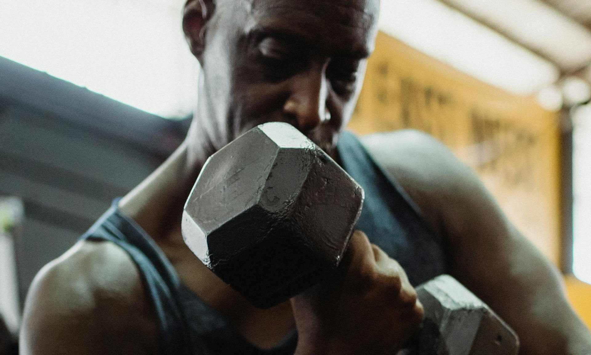 man holding dumbbells bicep curl gym
