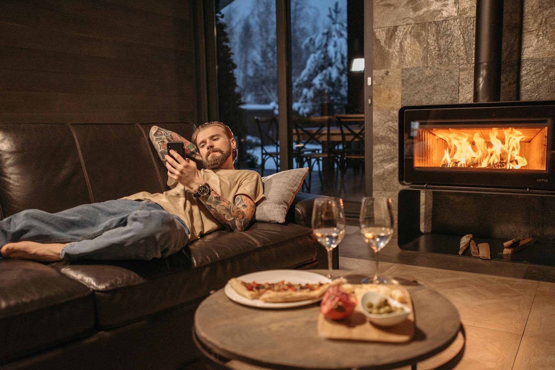 a man on the couch with pizza and wine