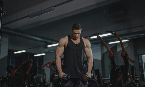man hoilding dumbbells weights in gym