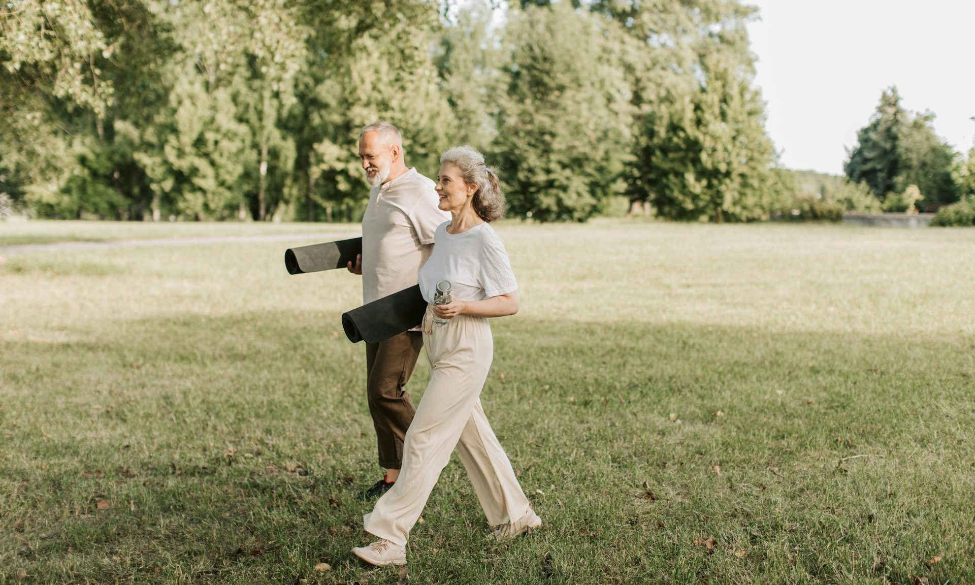 older couple with yoga mats walking outside
