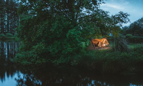 Woman camping inside of CanvasCamp's Mouflon tent on the side of a river.
