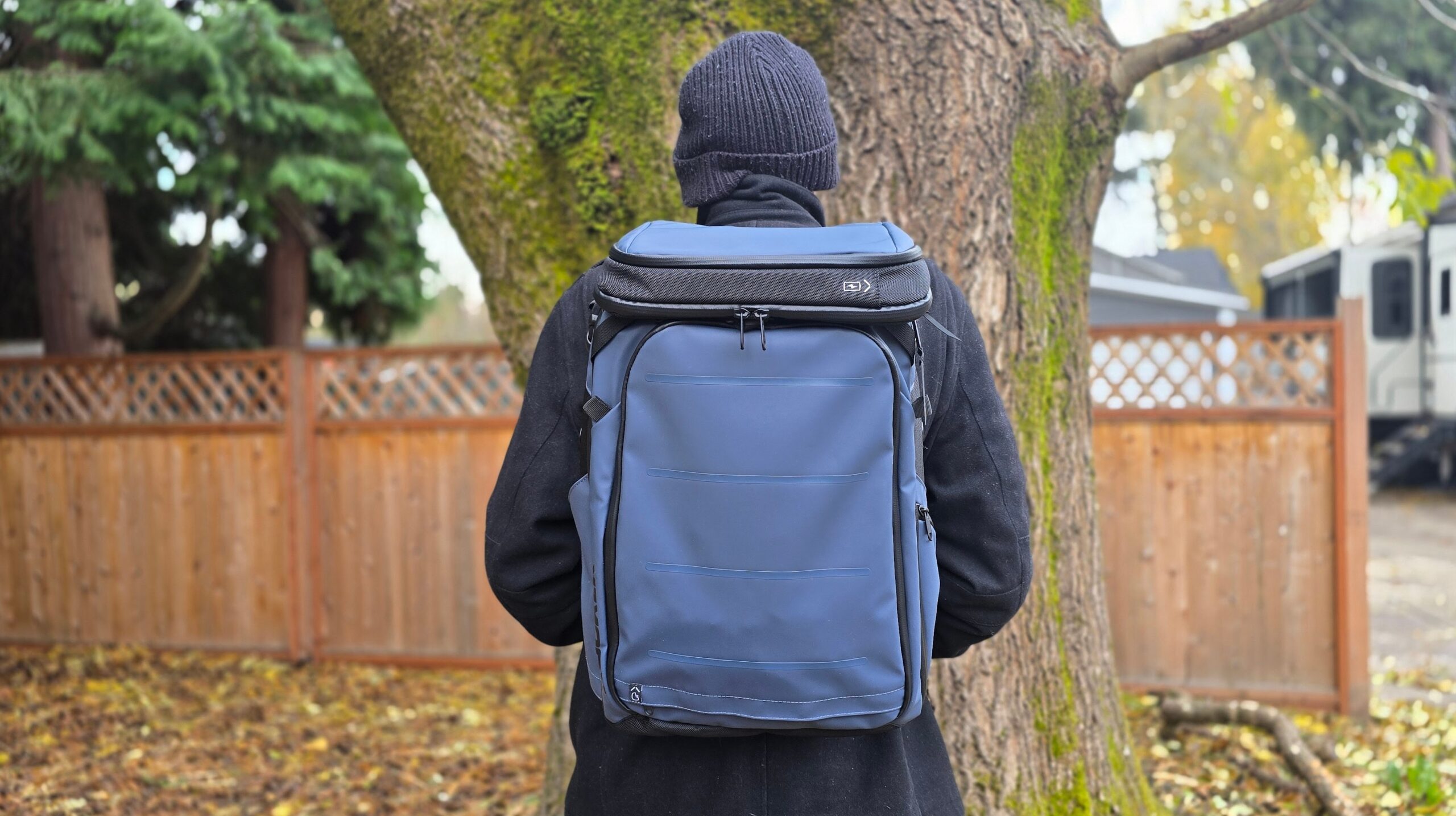 Bag, Backpack, Adult standing in front of a tree