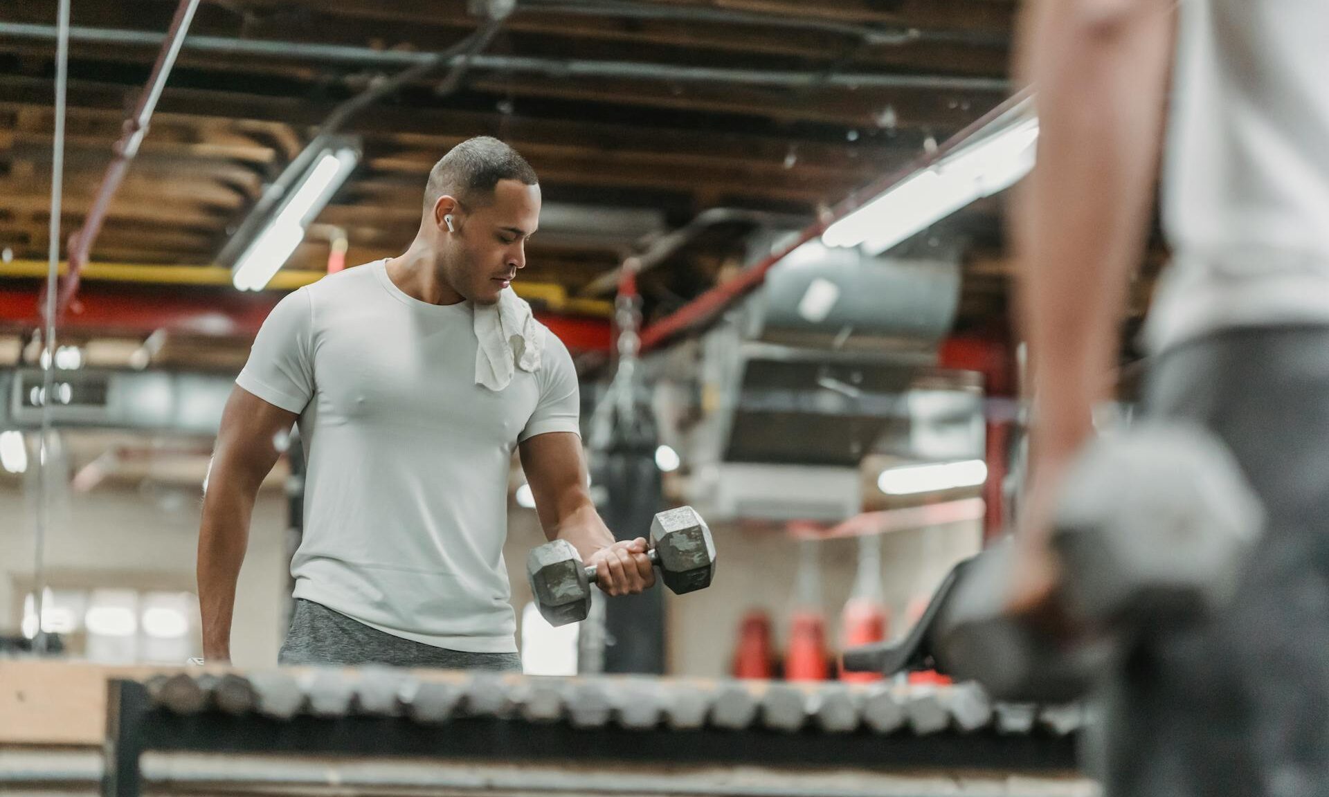 man lifting dumbbells bicep curl weights gym