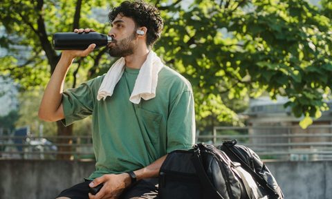 man drinking sport drink water outside after exercise