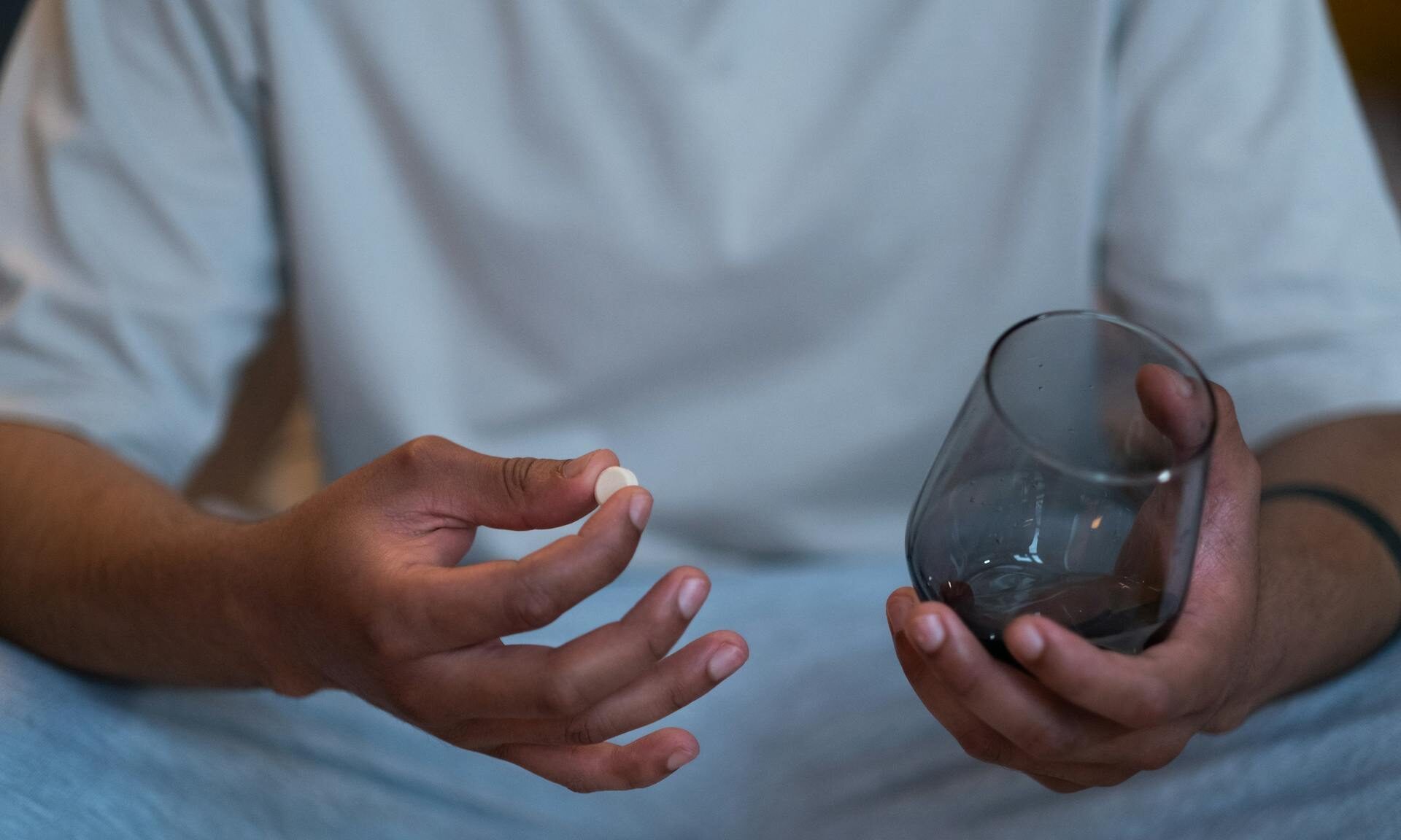 man taking supplement with water