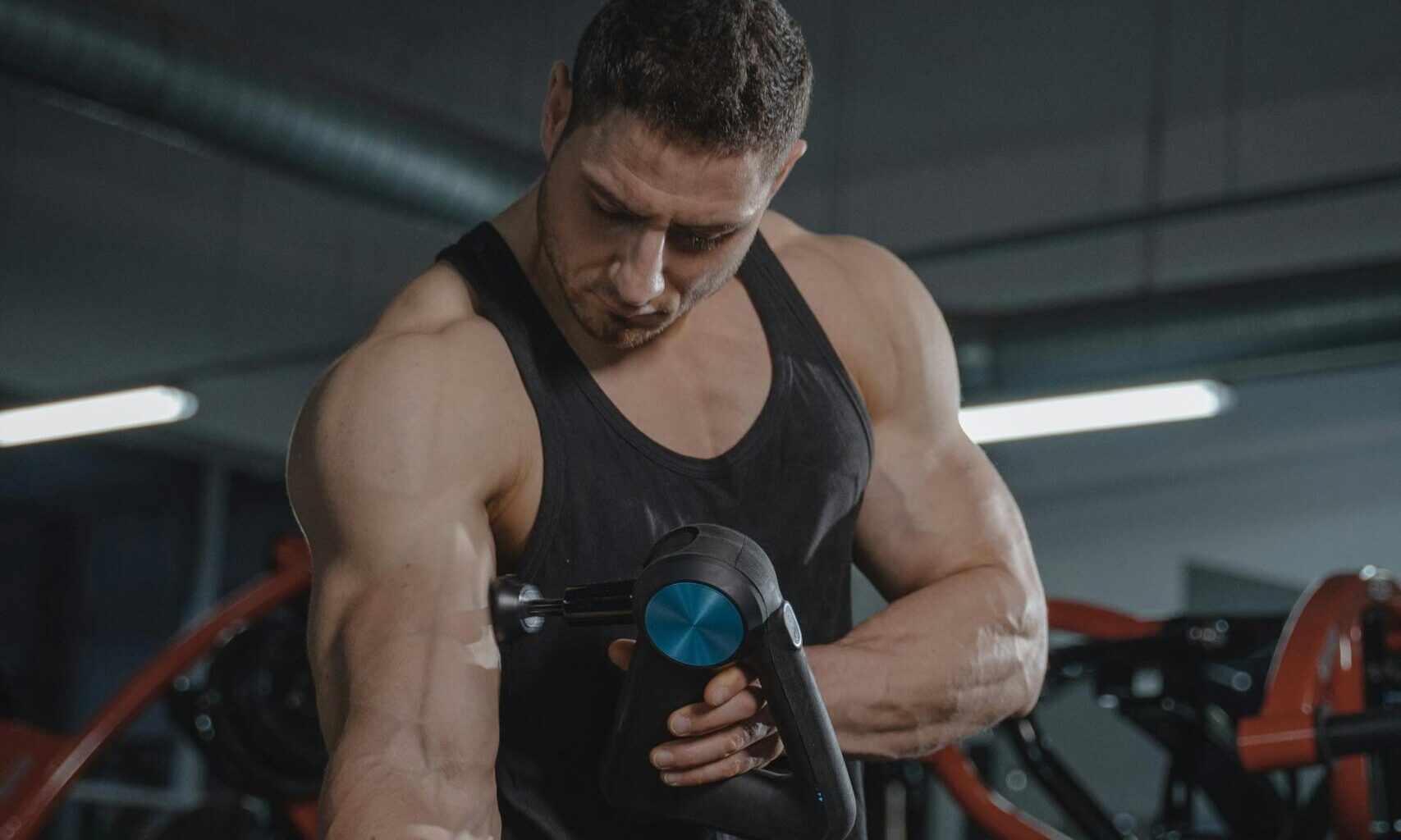 muscle man using handheld massage tool