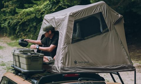 Man camping inside a Snow Peak Field Rise inflatable rooftop tent.