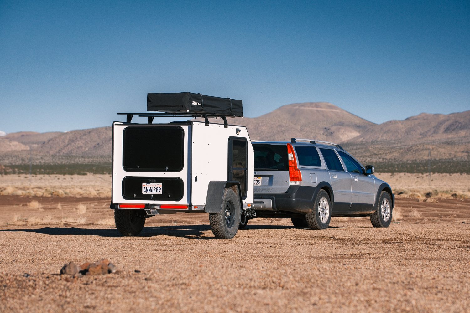 Rear view of Ecno Evil's Unit-1 pod camper/travel trailer being towed by a Volvo wagon in the mountains.