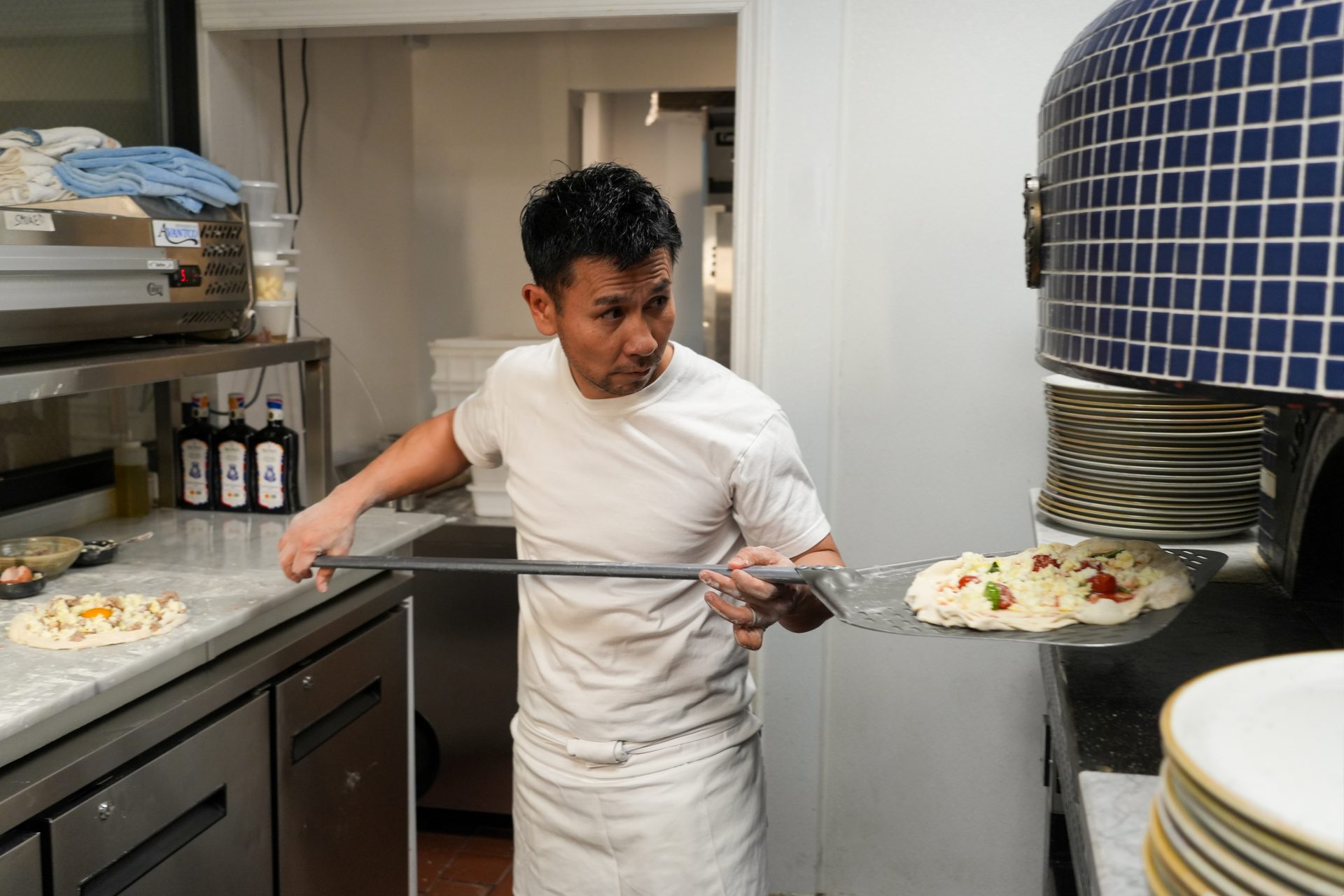 Chef Tamaki holding pizza in front of oven