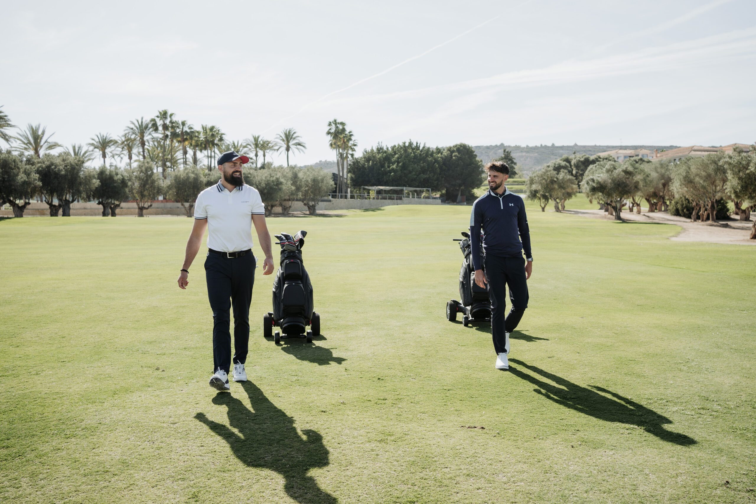 Two golfers walking with their golf bags on a course in Spain
