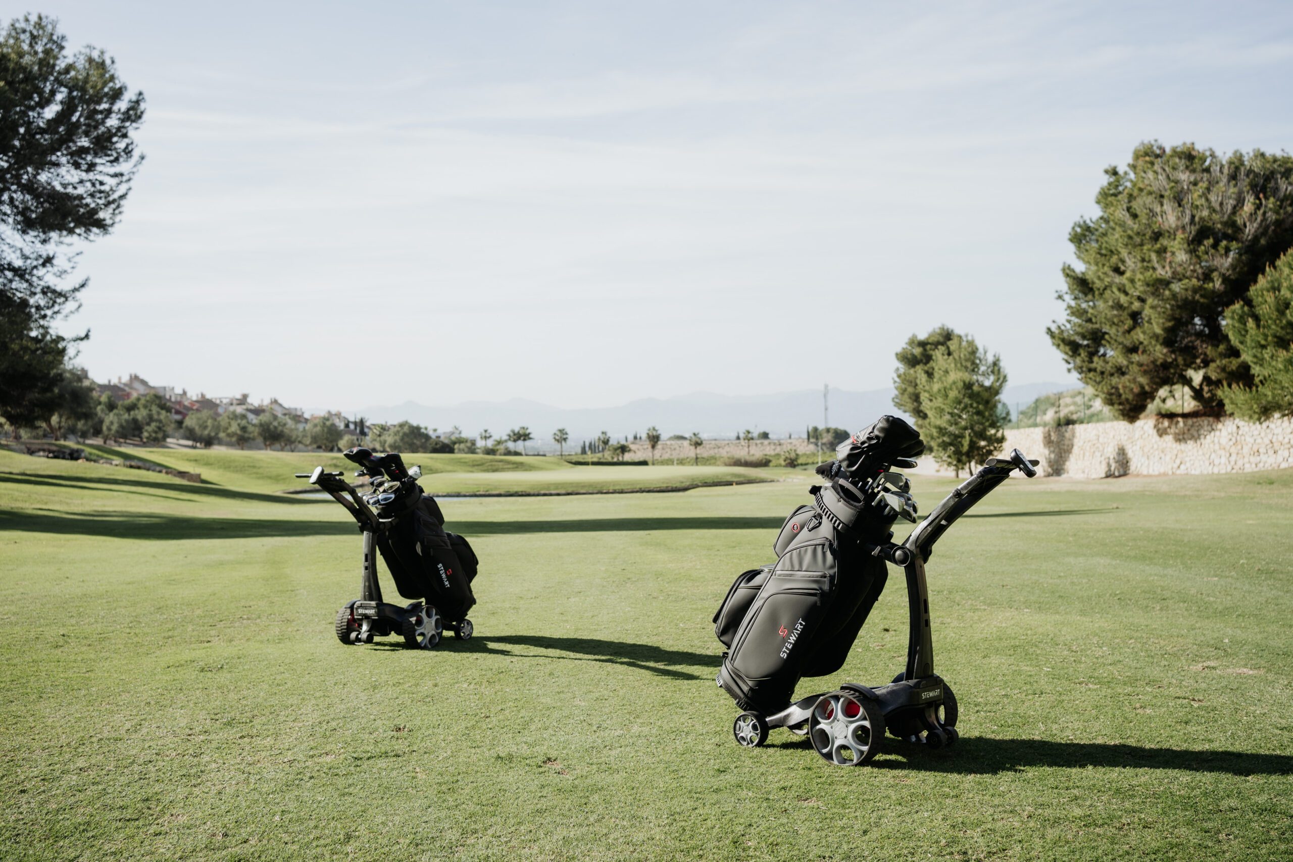 Two golf bags on push carts overlooking a golf course in Spain