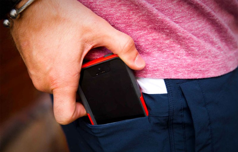 A person putting an iPhone into their pocket
