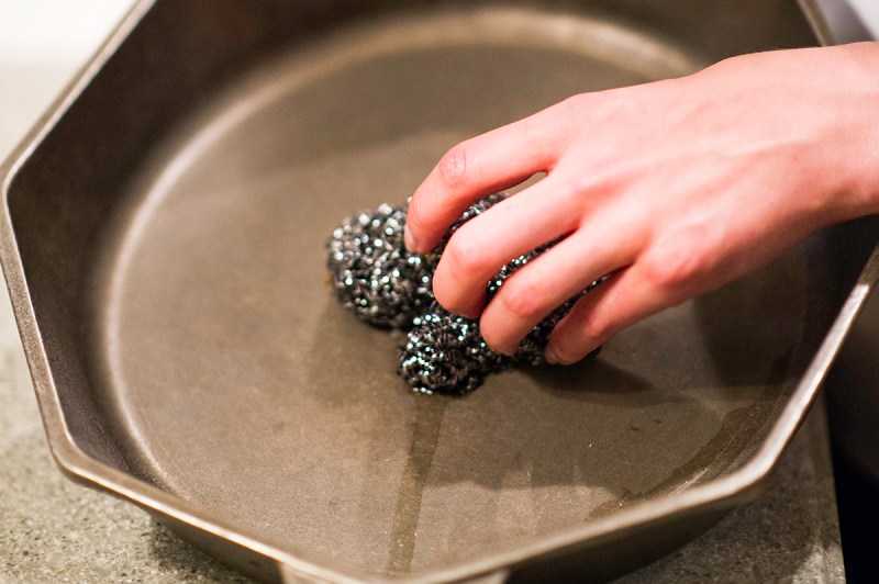 Person cleaning a cast iron pan.