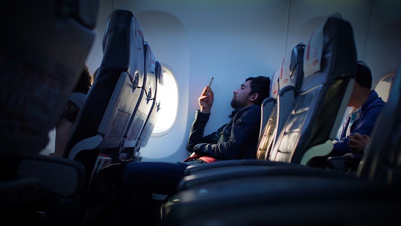 Passenger on their phone in the cabin of the plane.