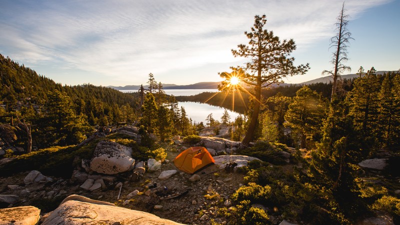 Mountain and lake landscape with sun overhead.