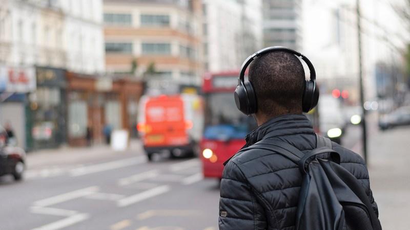 A man listening to a podcast while waiting for public vehicle.