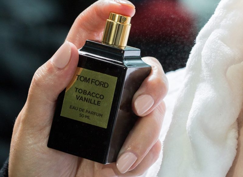 Someone spraying a Tom Ford cologne on themselves.