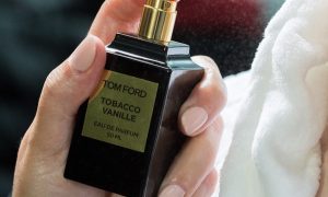 Someone spraying a Tom Ford cologne on themselves.