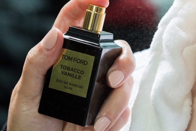Someone spraying a Tom Ford cologne on themselves.