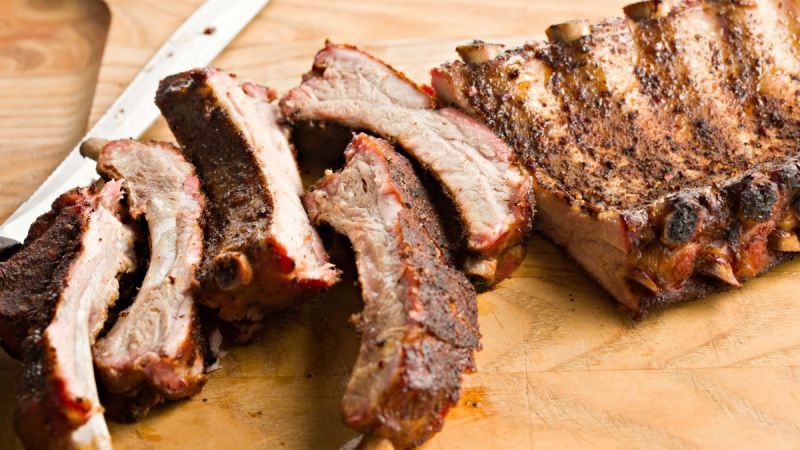 Deliciously smoked ribs chopped finely in a wooden cutting board.