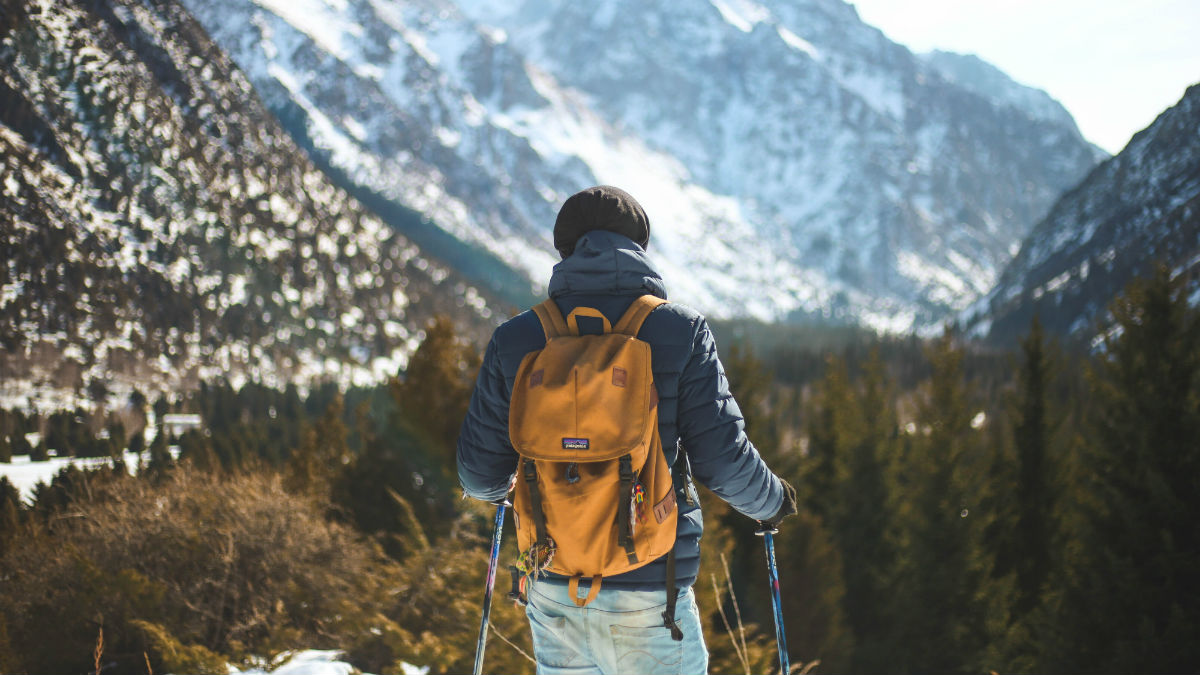 Man hiking with poles near a mountain