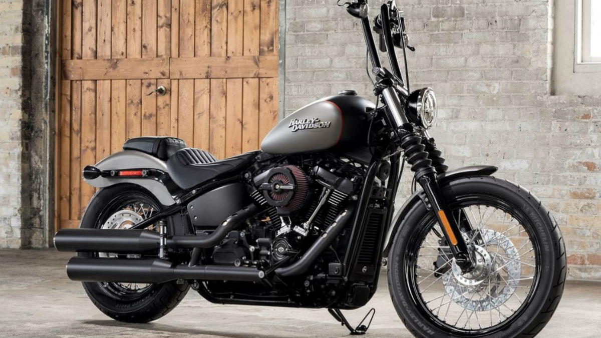 Front end angle of 2018 harley davidson street bob parked inside a brick building with a wooden barn door in the back.