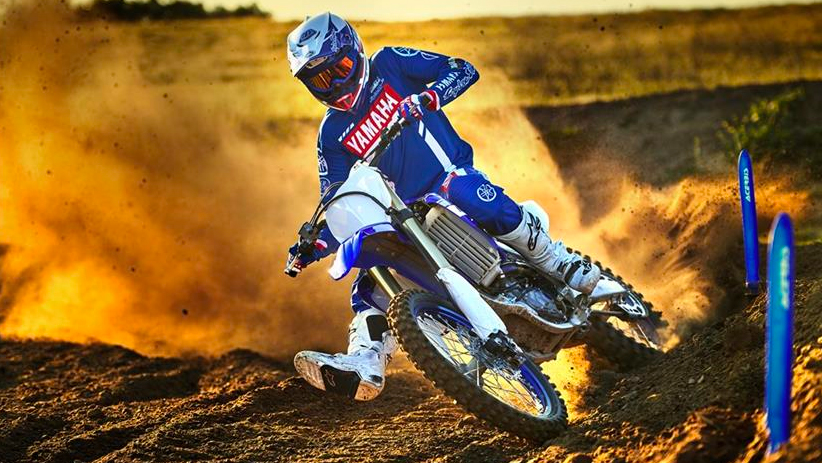 Motorcycle rider on a Yamaha YZF450 going around a corner at high speed with dust behind the rear wheel.