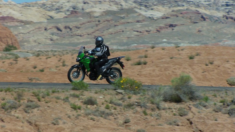 Motorcycle rider on a Kawasaki VERSYS X riding through the desert with dry mountains in the back.